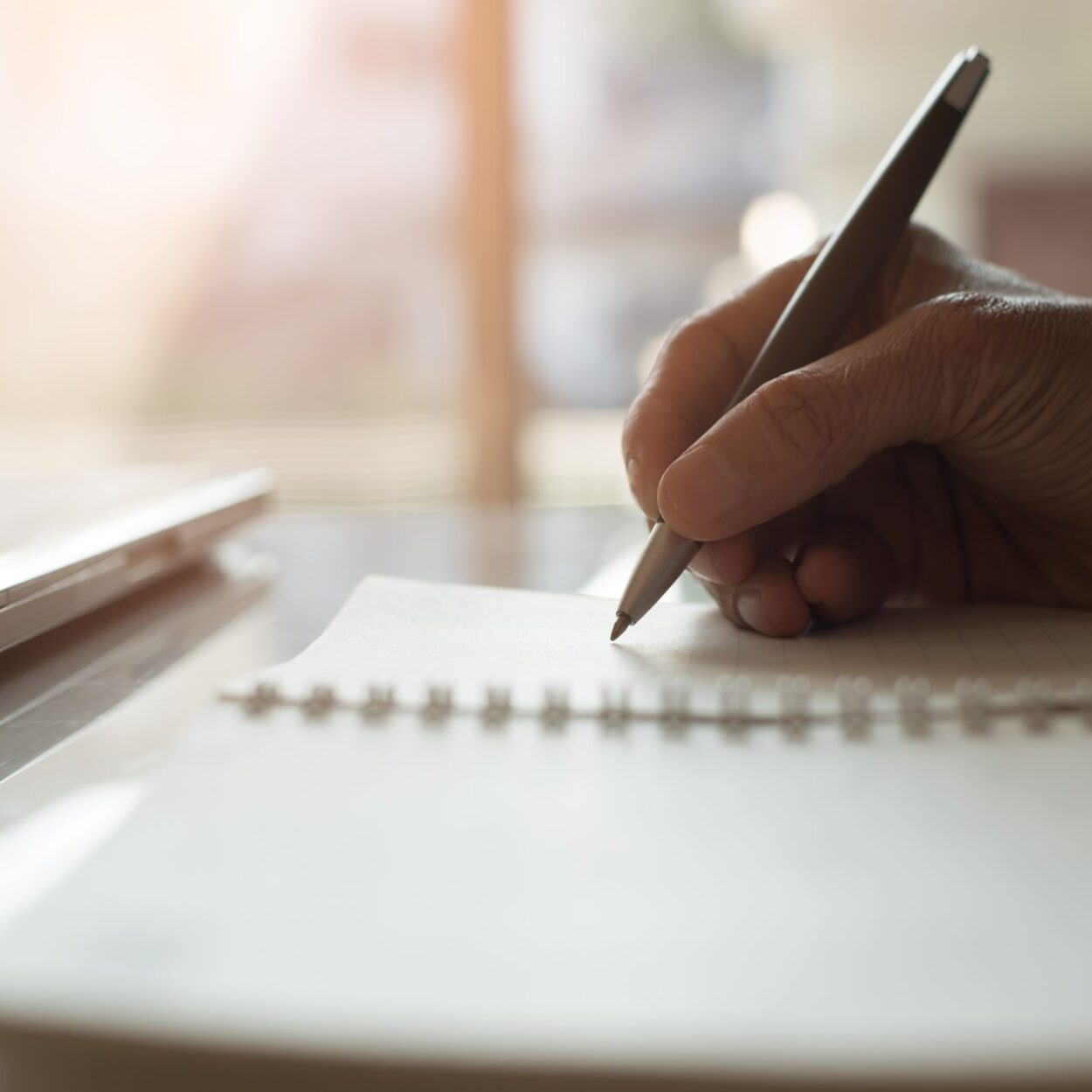 a person writing on a piece of paper with a pen.