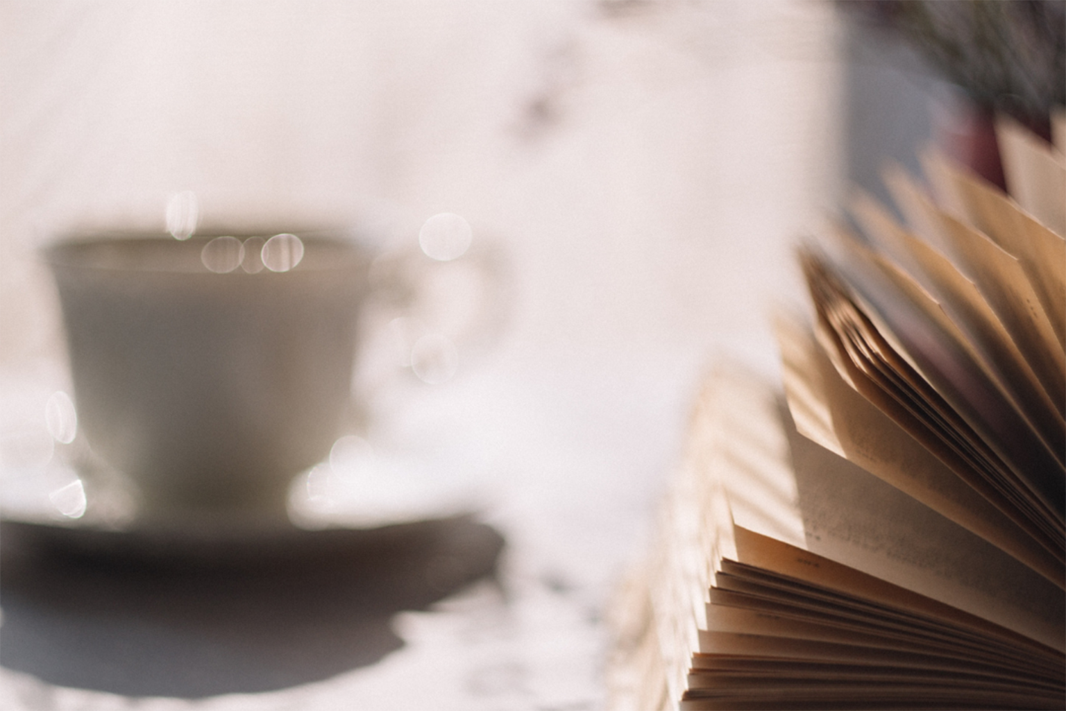 an open book and a cup of coffee on a table.